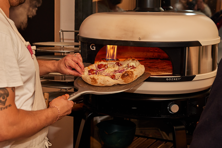 someone pulling a pizza out of an oven