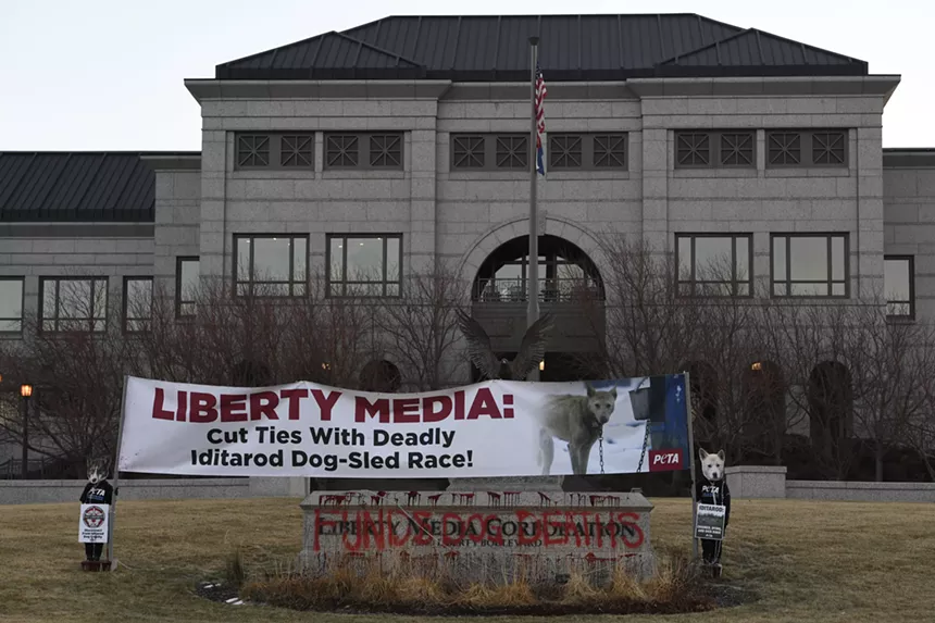 People stand in front of a large building with a banner.