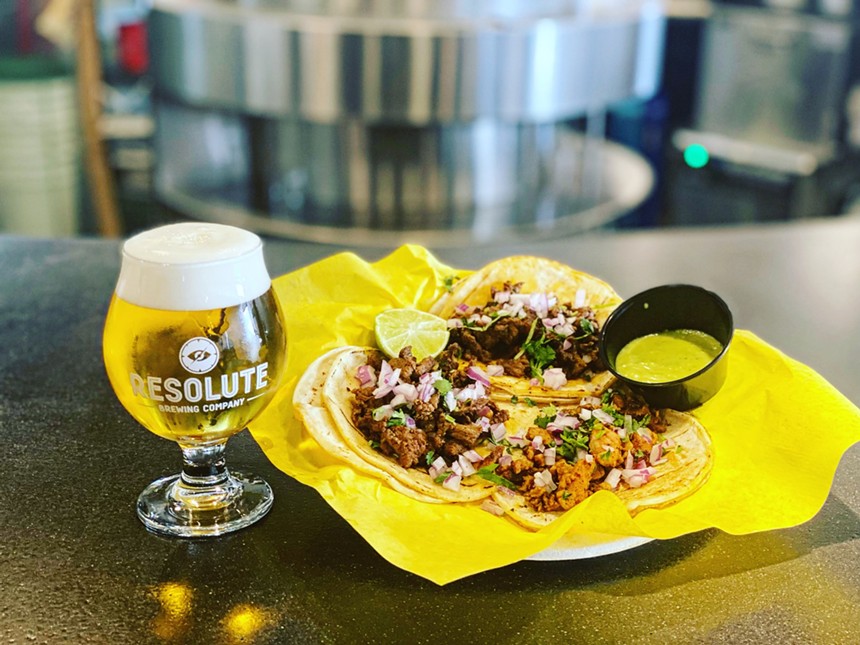 tacos on a plate next to a glass of beer