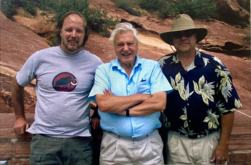 Three men pose in front of a camera.