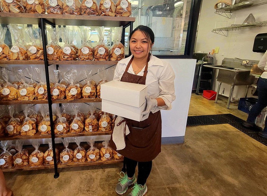 A woman standing and holding pastry boxes