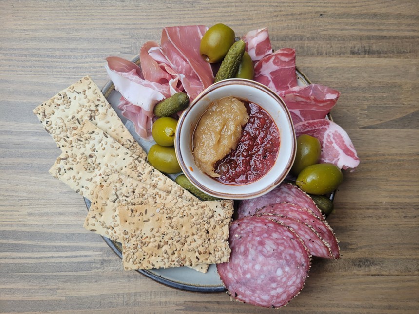 plate with meat slices, crackers, olives and pickles