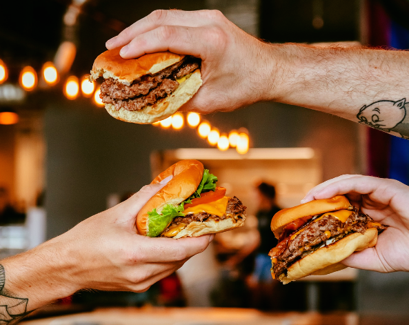three hands holding burgers