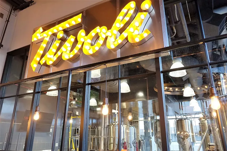 Lit up brewery sign with fermenters.