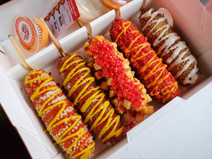 a box filled with corn dogs with different toppings
