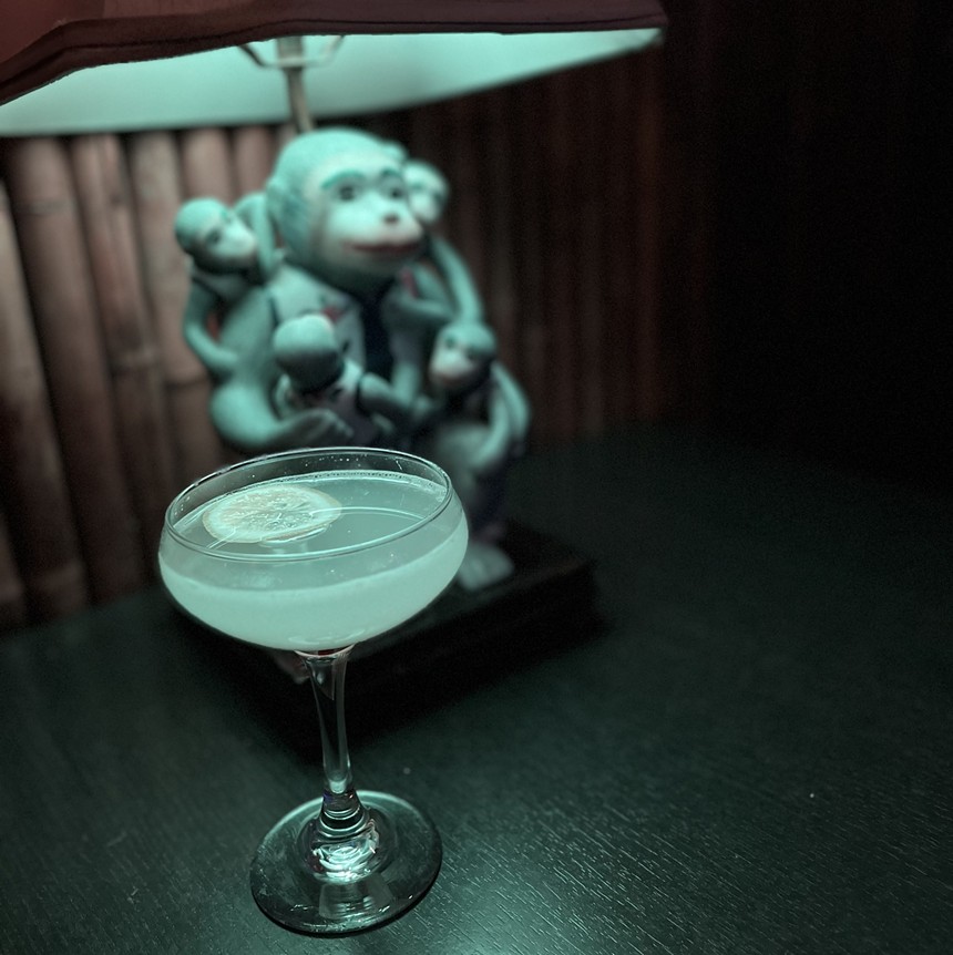 a cocktail in a coupe glass in front of a monkey lamp