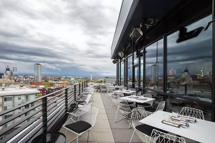 tables and chairs on a rooftop patio with city views