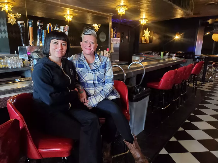 two women sitting on bar stools posing
