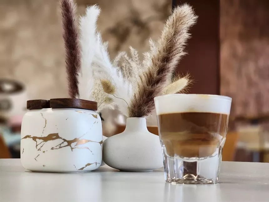 coffee in a glass cup in front of a small white vase