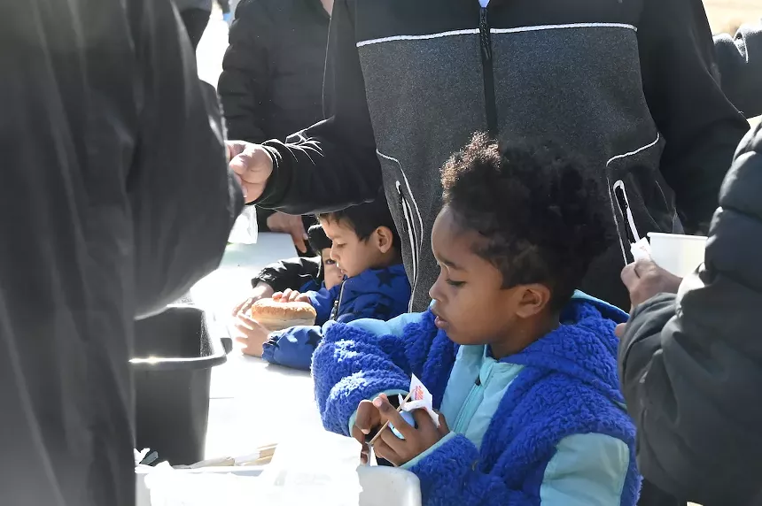 Migrant children wait for food.