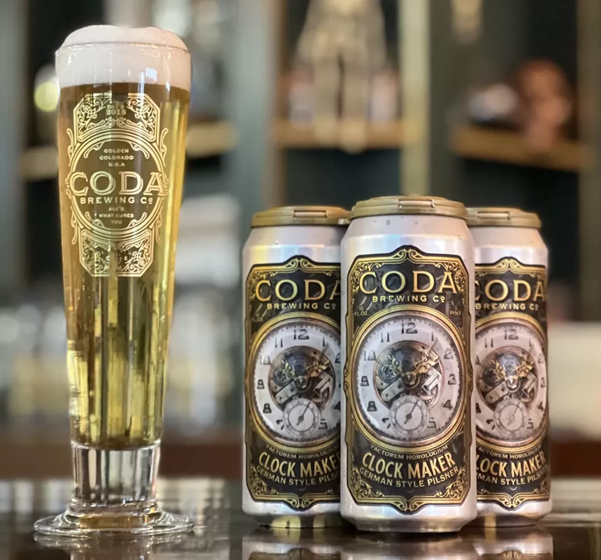 A pale lager in a pilsner glass and cans of beer.
