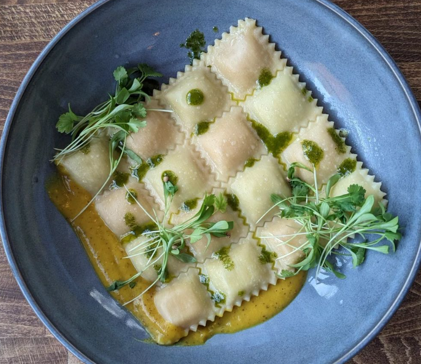 ravioli on a blue plate with microgreen garnish
