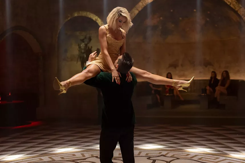 man lifting up woman in gold dress while dancing