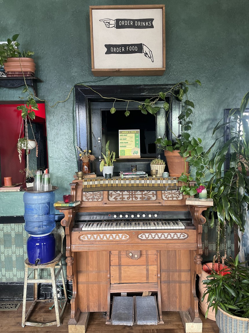 an organ under a small window with houseplants on and around it