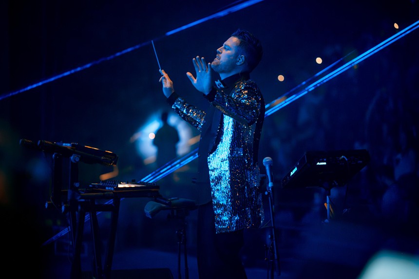 a man conducting an orchestra in a sequin jacket