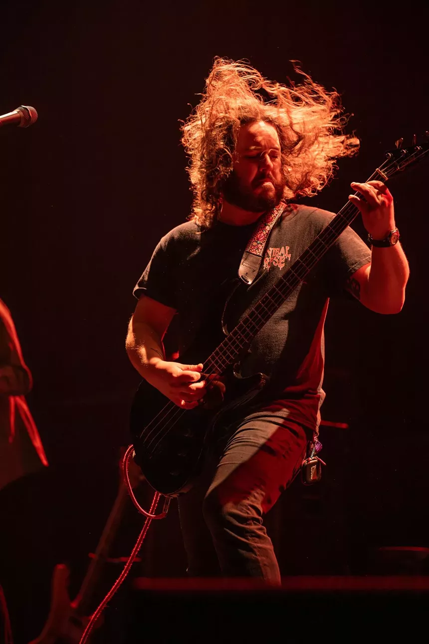 man with long hair playing guitar