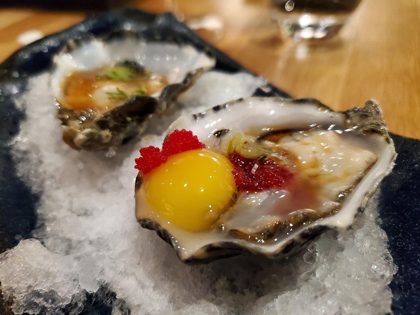 two oysters on ice, one with a quail egg on top.