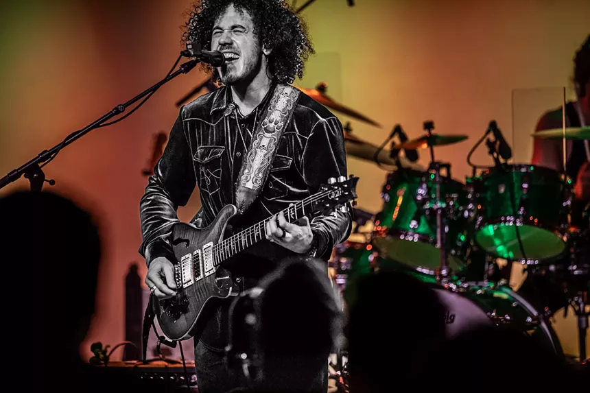 guitarist on stage singing into a microphone