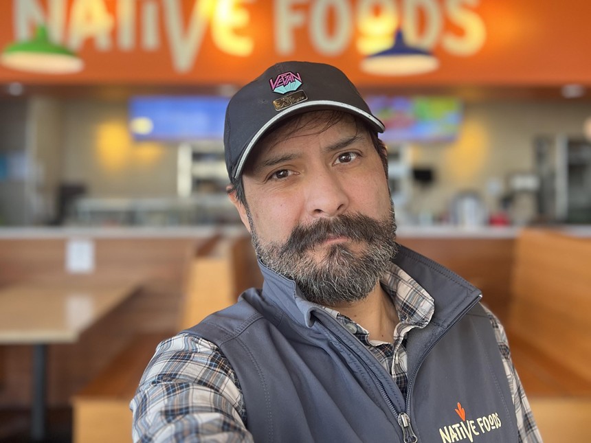 A headshot of a man, Michael Olivas, backdropped by Native Foods' restaurant interior