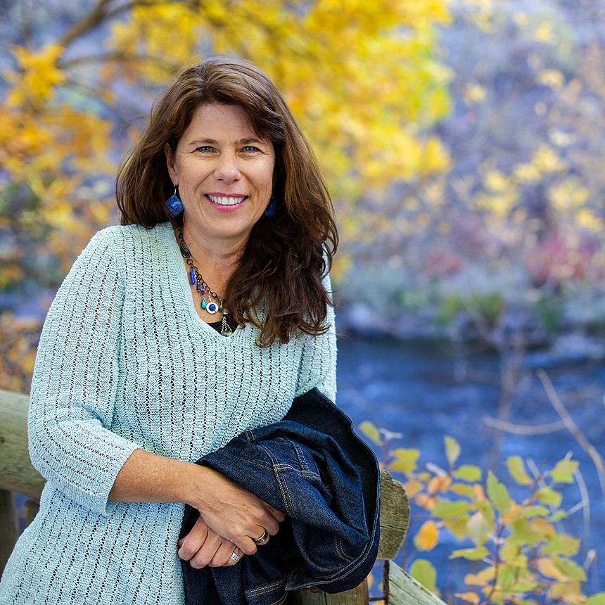 woman in white sweater holding jacket in fall colors