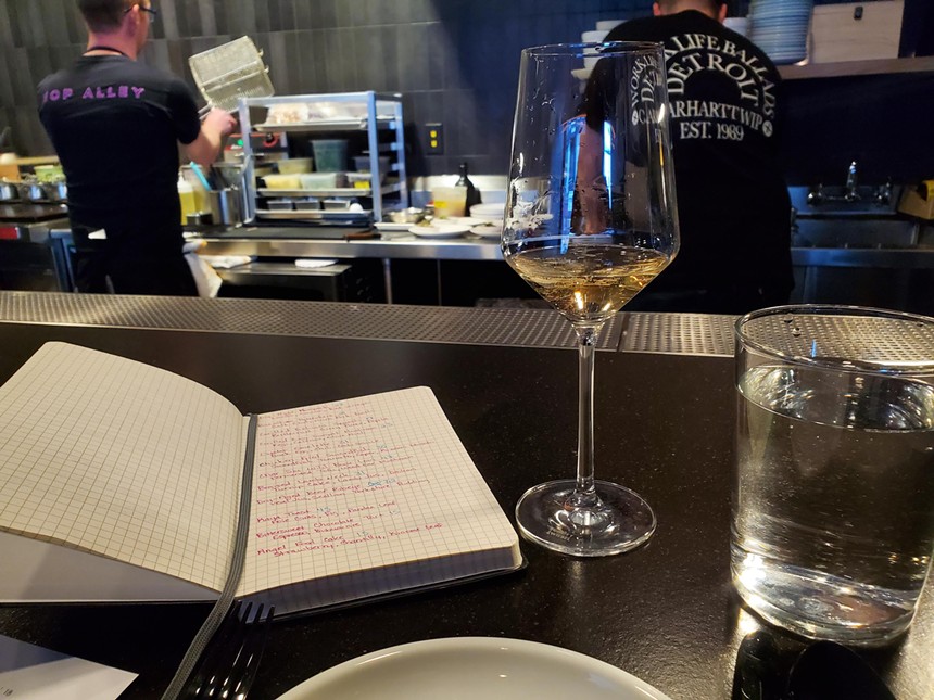 an open notebook on a counter next to a glass of wine