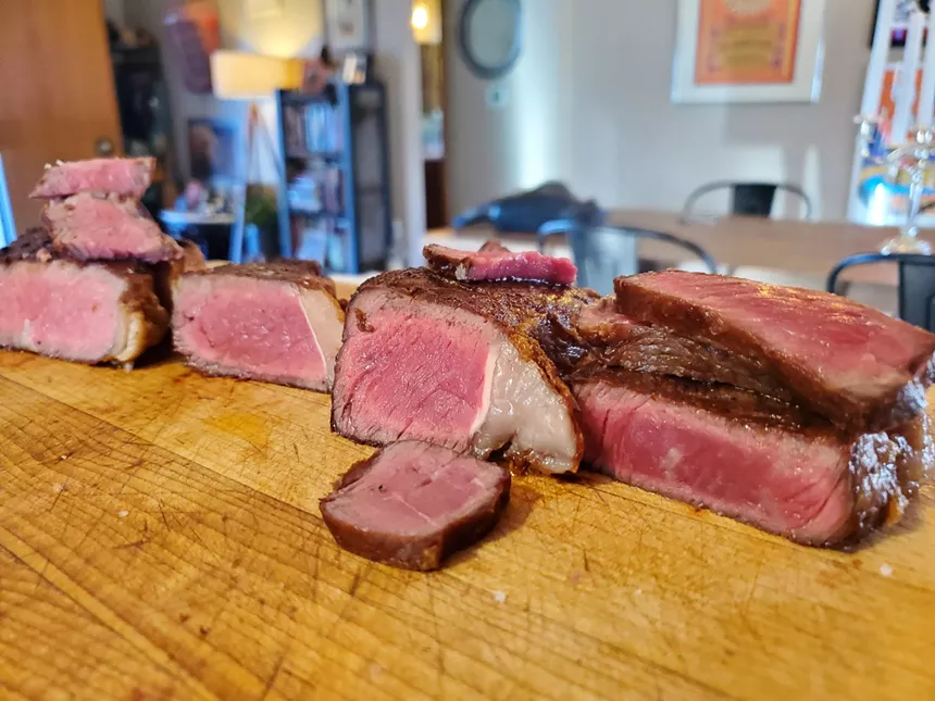 various cooked and sliced steaks on a wooden board