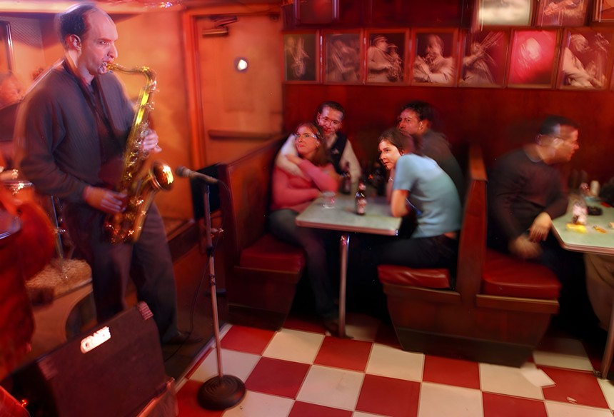 man on saxophone while people listen in booths
