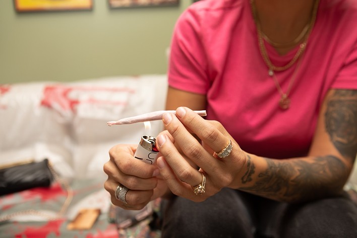 Woman with tattoos lights a marijuana joint
