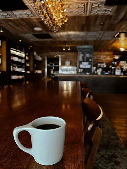 coffee in a white mug sits on a wood table