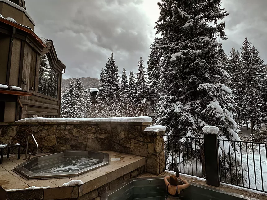 two hots tubs outside with snowy trees behind it