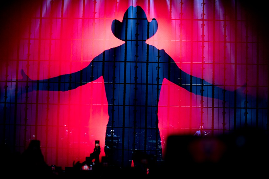 silhouette of a man in a cowboy hat with his arms stretched out