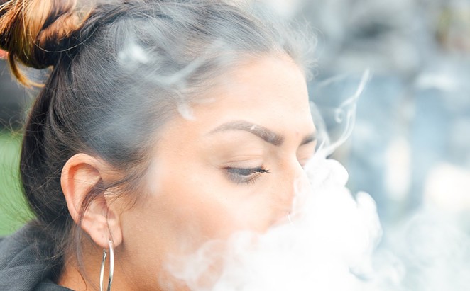 Woman blows cloud of smoke