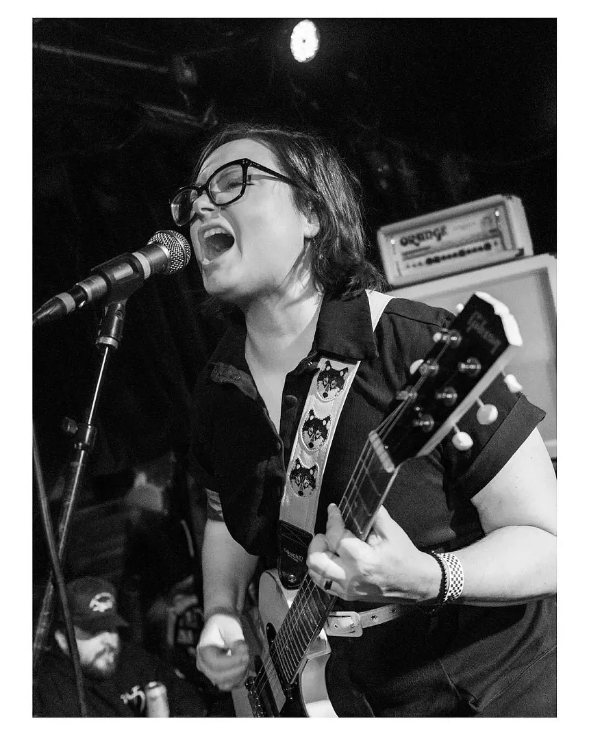 woman playing guitar singing into a microphone