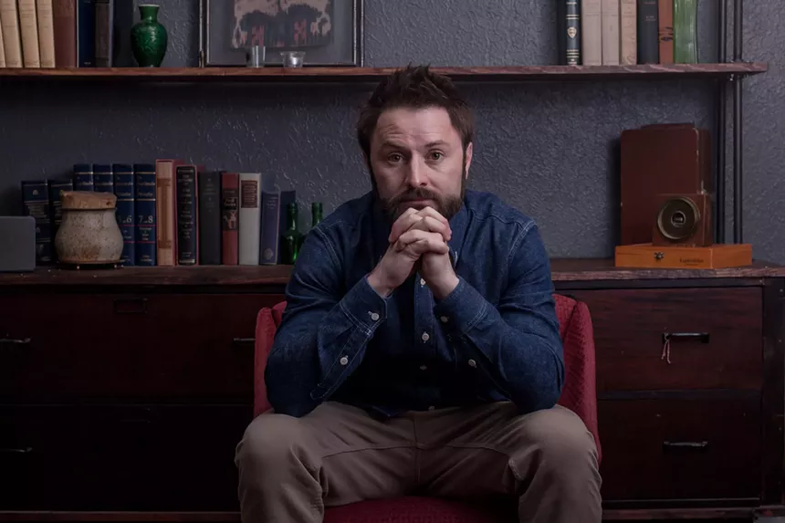 man in a jean shirt sitting in a chair