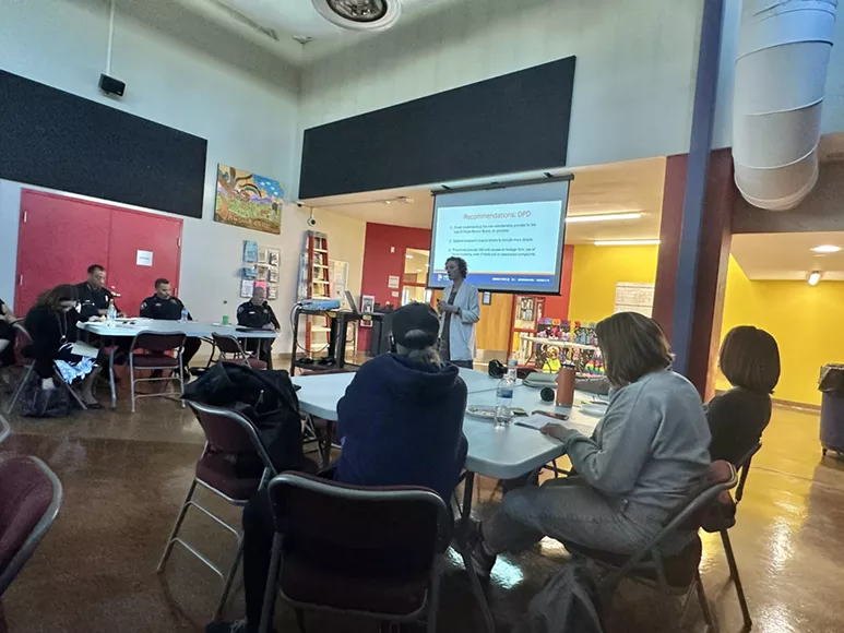 Woman speaks in front of projeciton screen at meeting