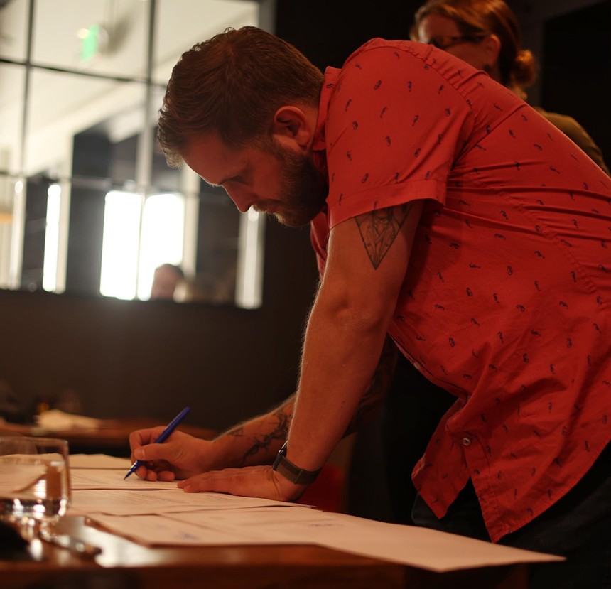 man in a red shirt signing paperwork