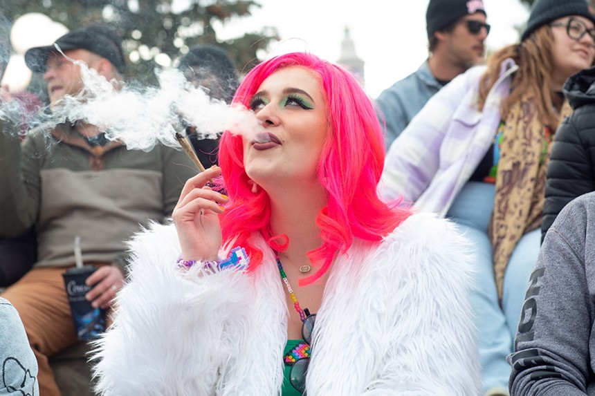 A woman in pink hair smokes a joint