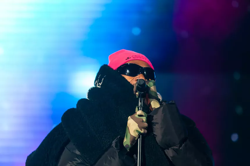 man in sunglasses and scarf at a microphone