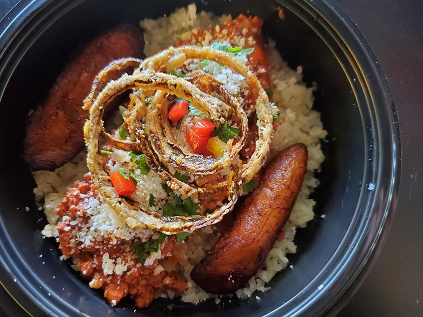 a bowl with fried plantains and onlin rings over cauliflower rice