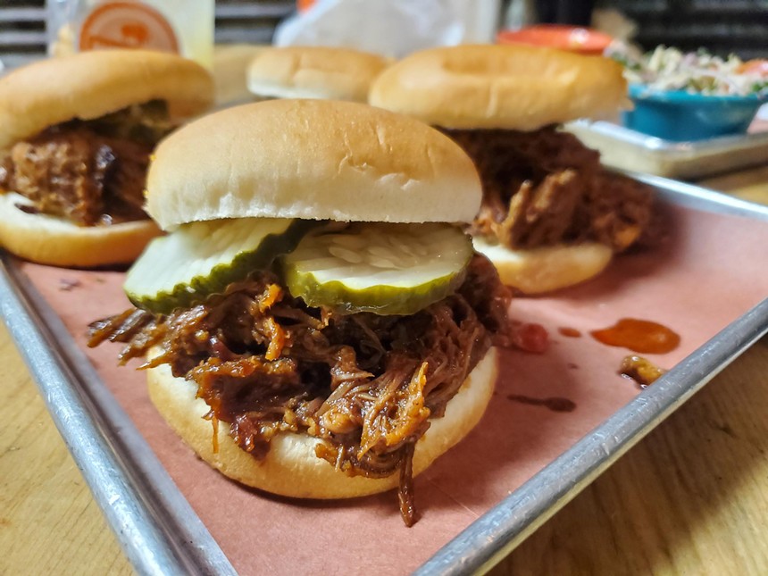 pulled barbecue meat on a hamburger bun with pickles