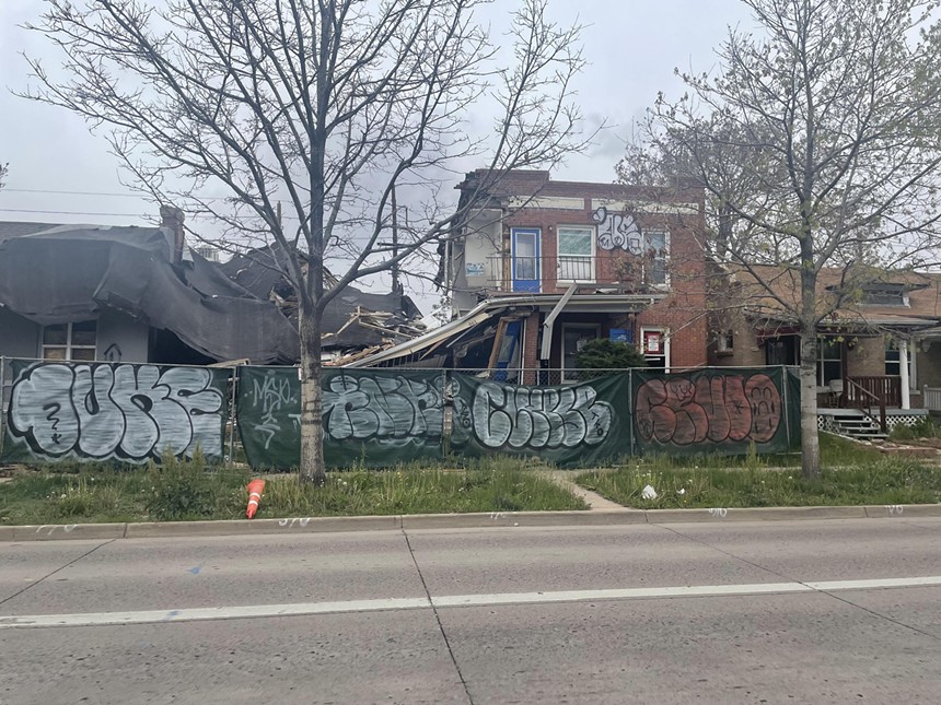 Fence with graffiti in front of destroyed house