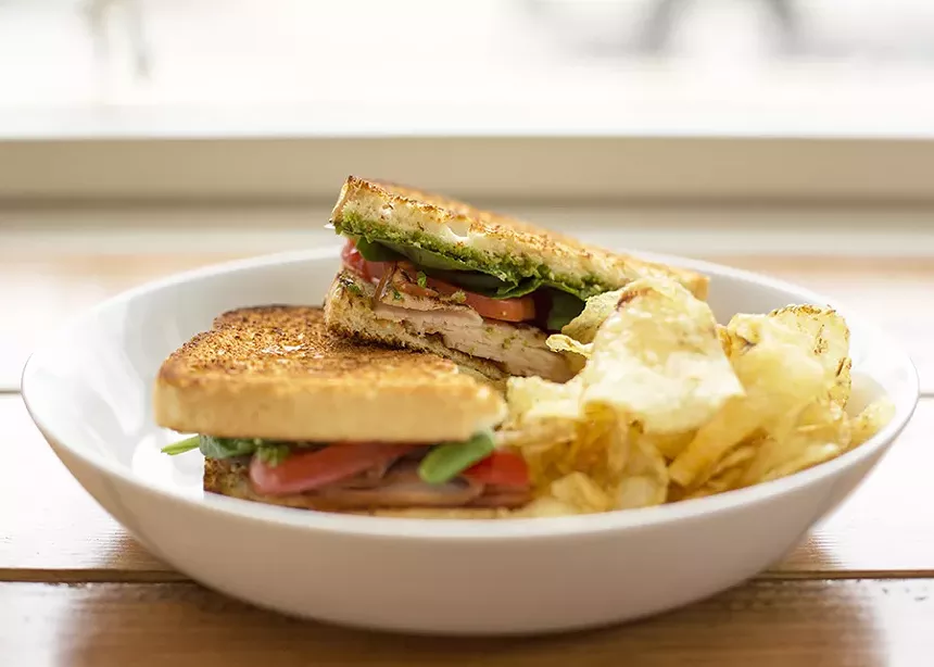 A sandwich and potato chips in a white bowl