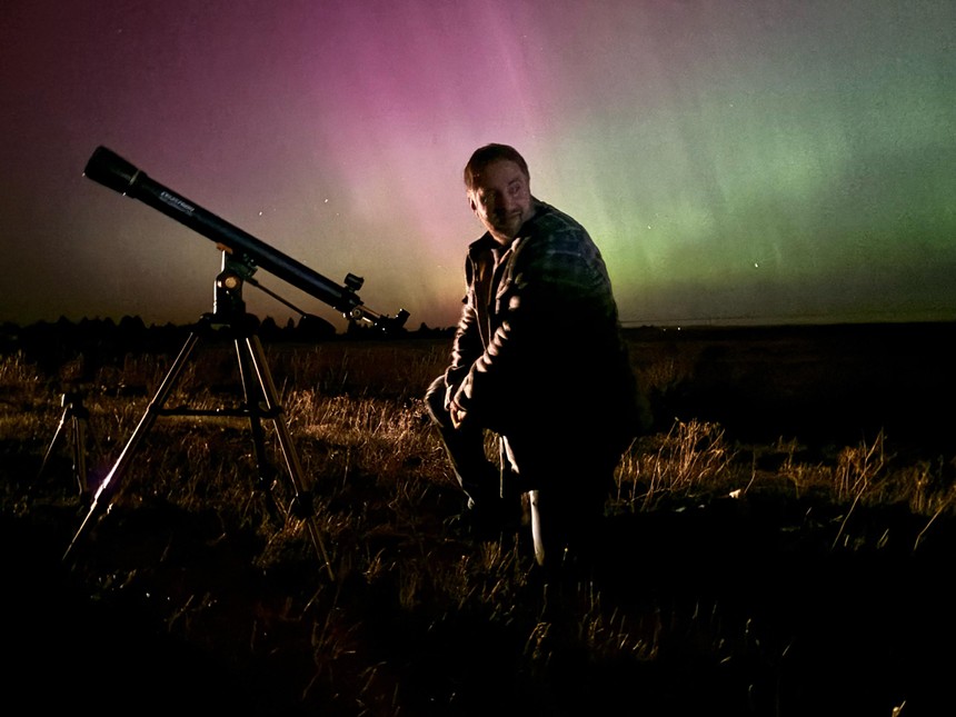 man with telescope, northern lights