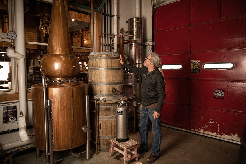 a man standing in front of distilling equipment
