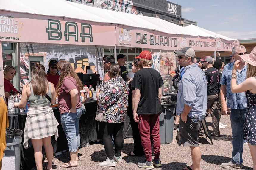 people standing outside in a line near a booth
