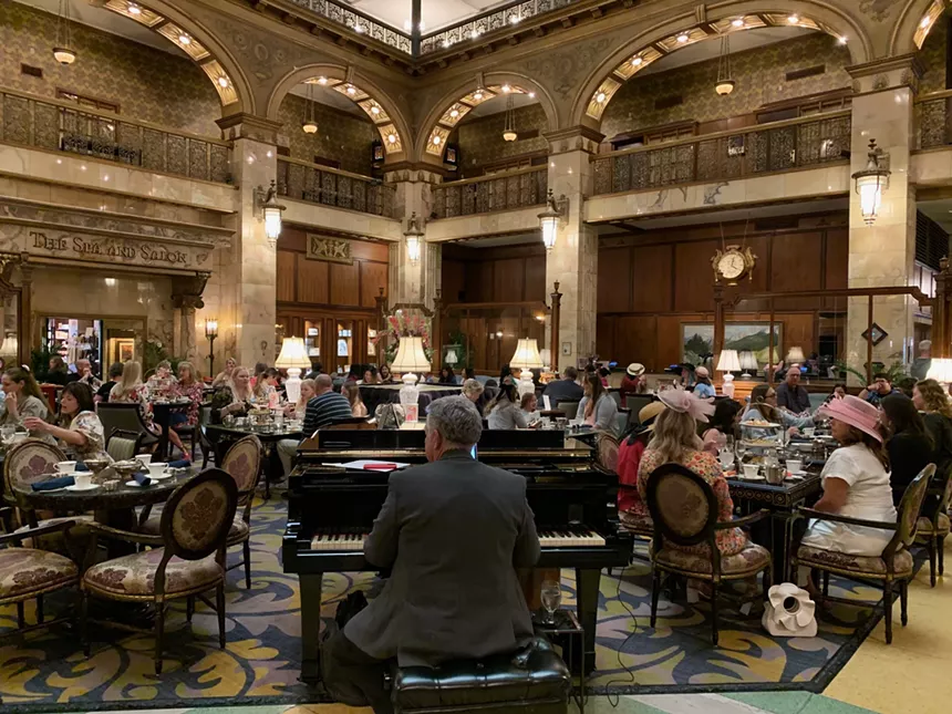 women in hats, man at piano in hotel lobby