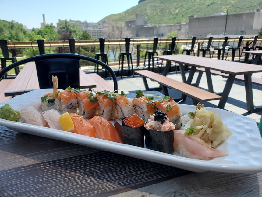 a plate of sushi on a table in front of a view of trees and a large building