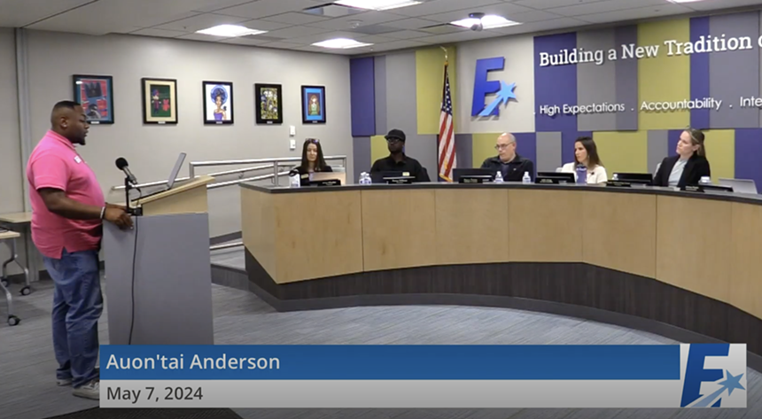 A man speaking to a board of education during a public meeting.