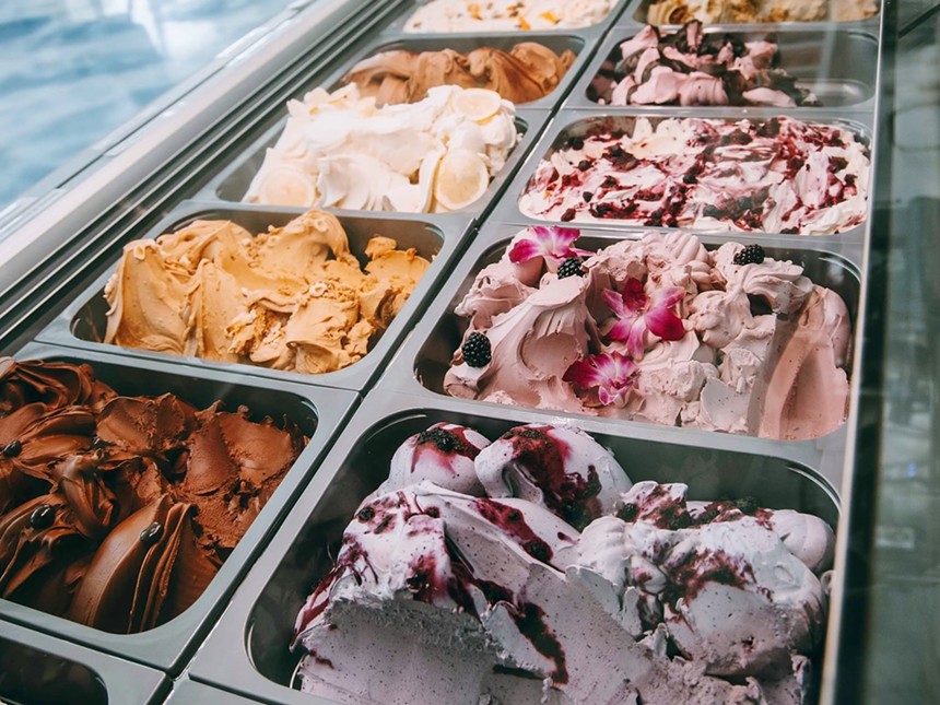 Tubs of different flavored gelato organized next to each other inside of a fridge.