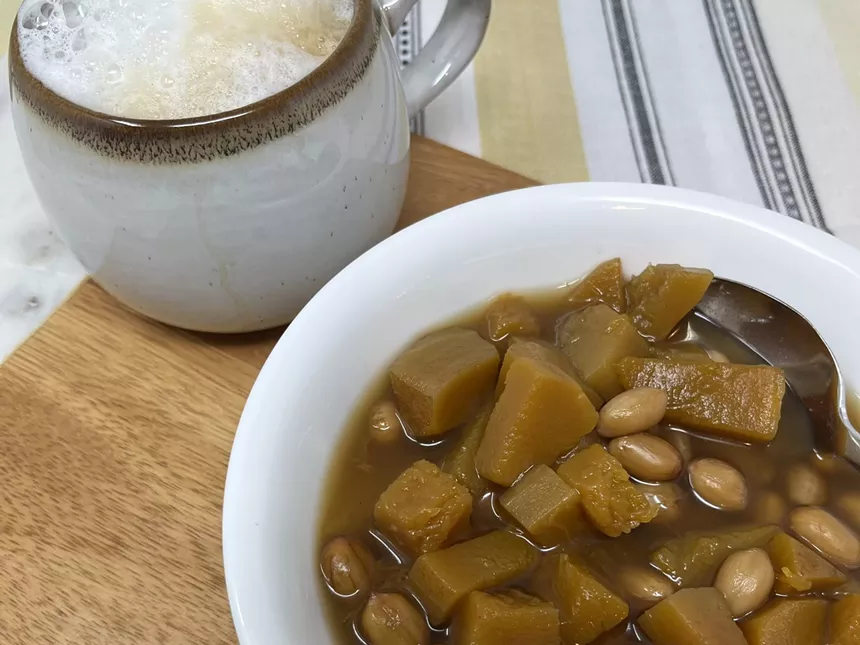 A bowl of dulce de calabaza next to a hot beverage in a white mug